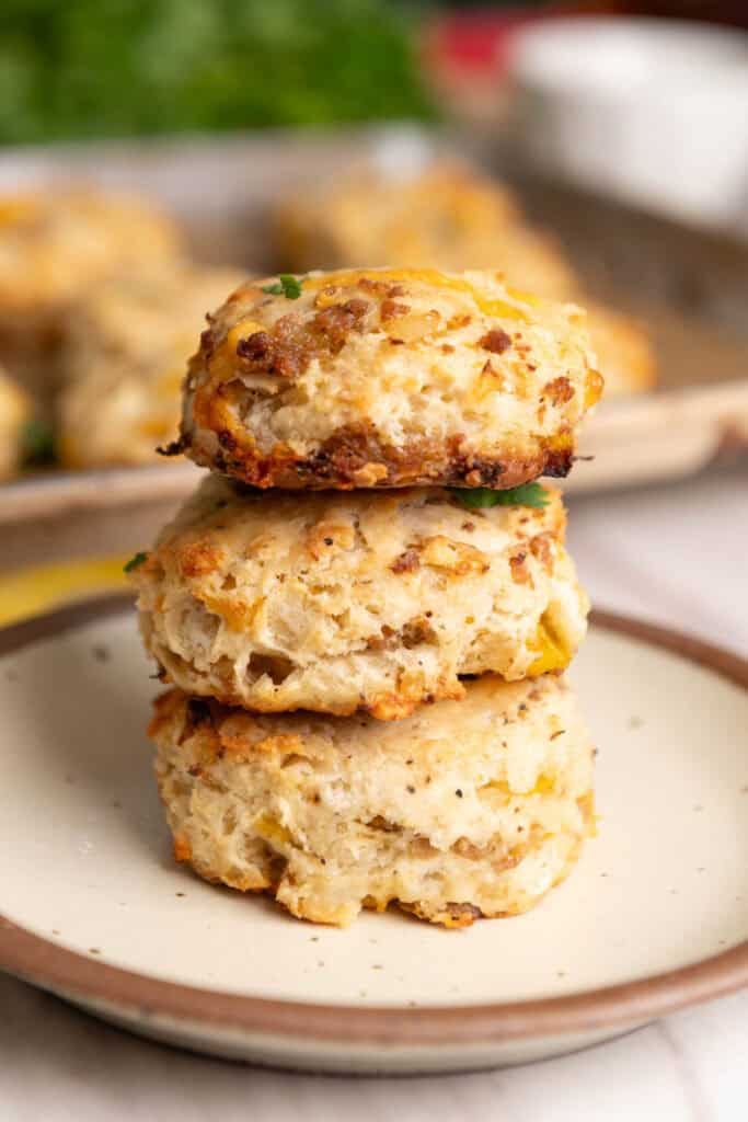 Three golden biscuits stacked on top of each other on a small brown-rimmed plate.