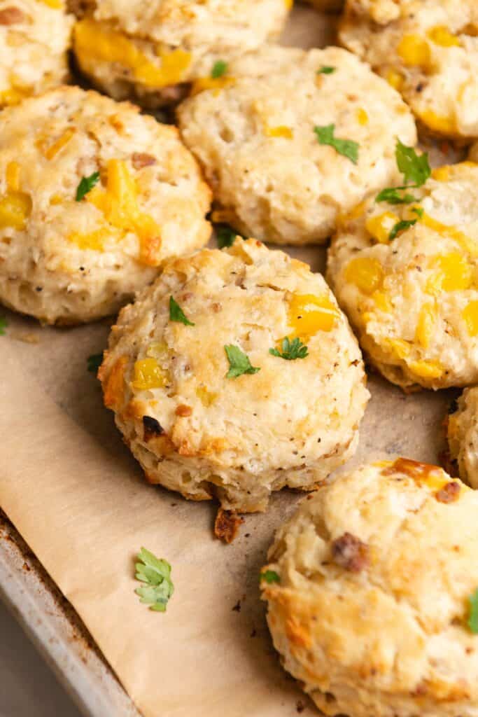 Side view of biscuits on a parchment paper lined baking sheet.