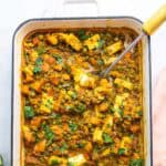 Top down view of white rectangular enamel baking dish filled with lentils, sweet potato, and paneer casserole.