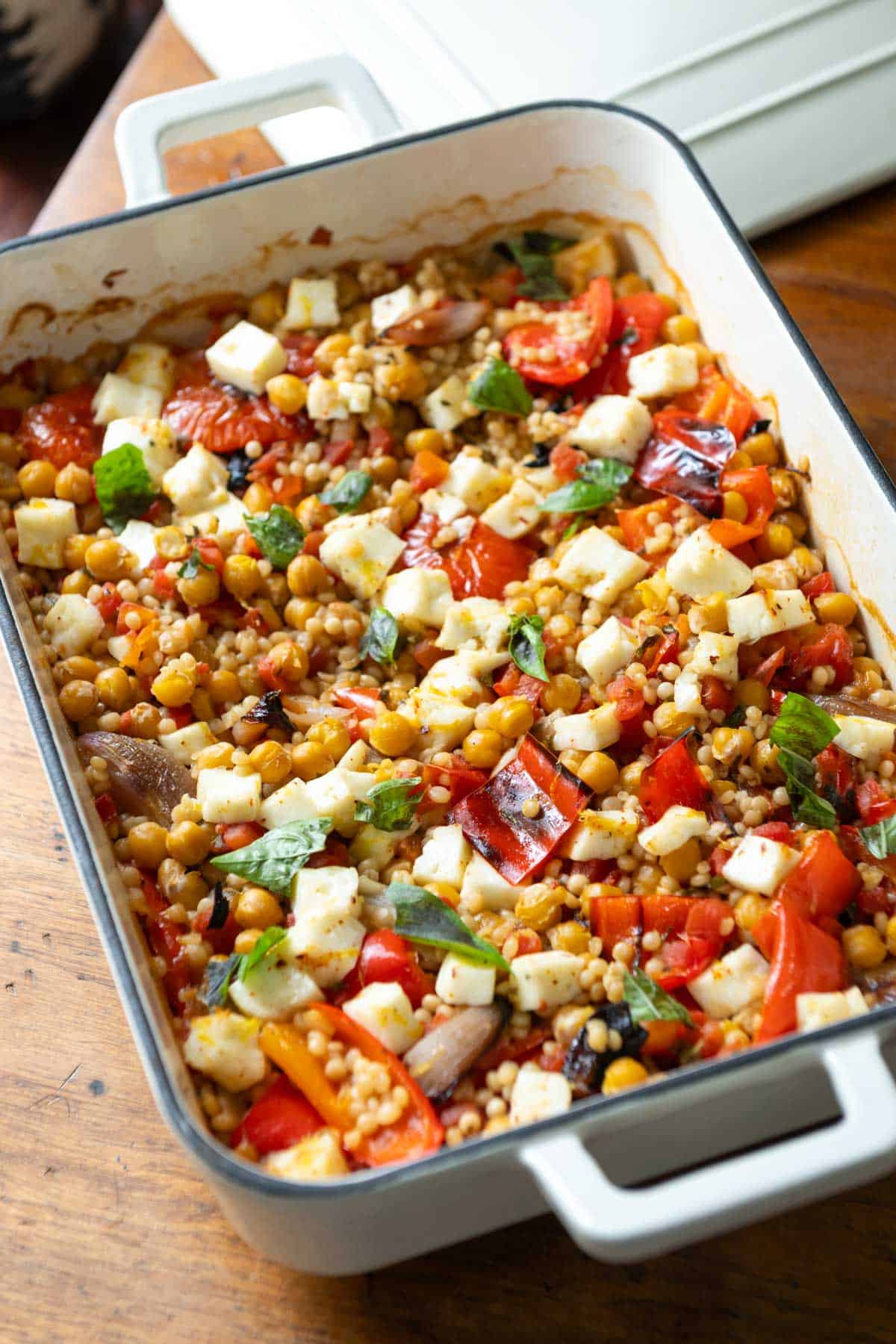 Side view of white enamel dish filled with couscous and roasted red peppers.