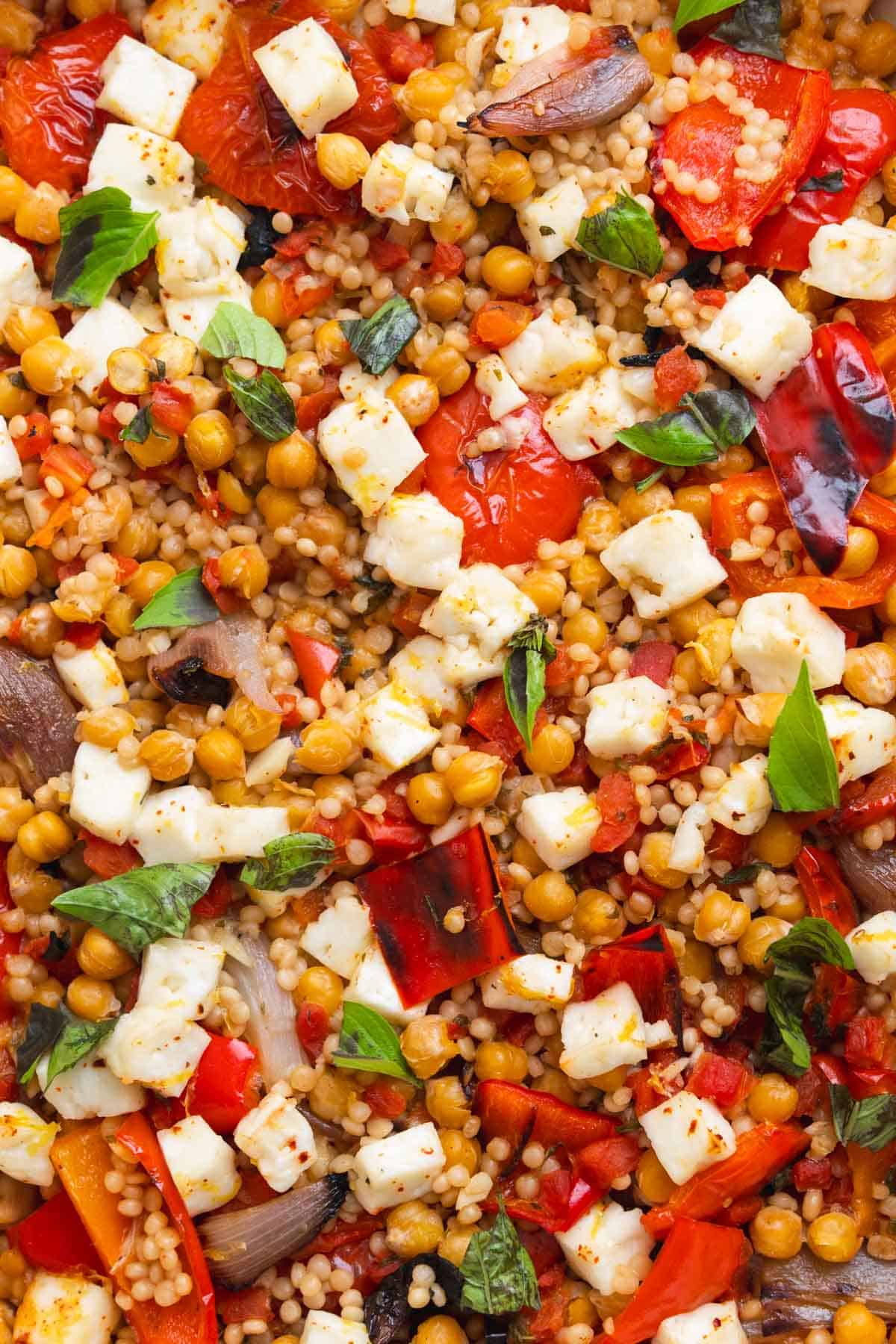 Close up of couscous casserole topped with baked halloumi and herbs.