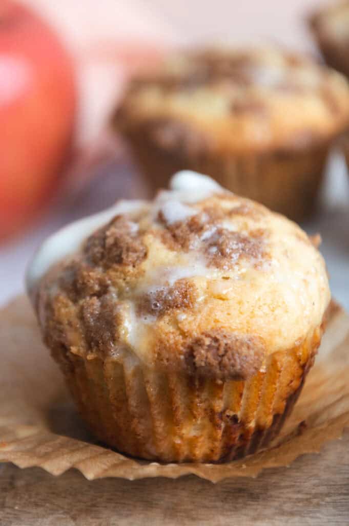 Close up side view of muffin topped with golden crumb topping and a drizzle of icing.