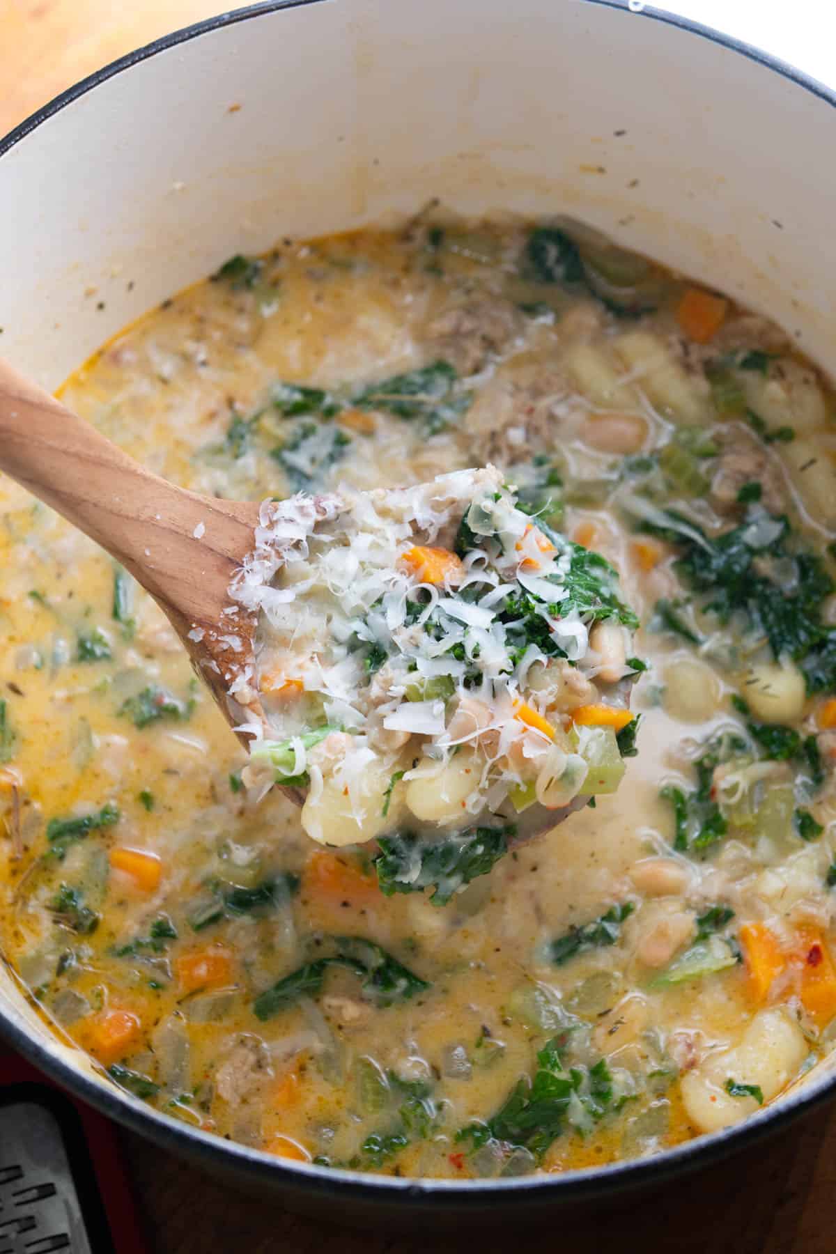Ladle of soup topped with grated Parmesan with more soup in the background.