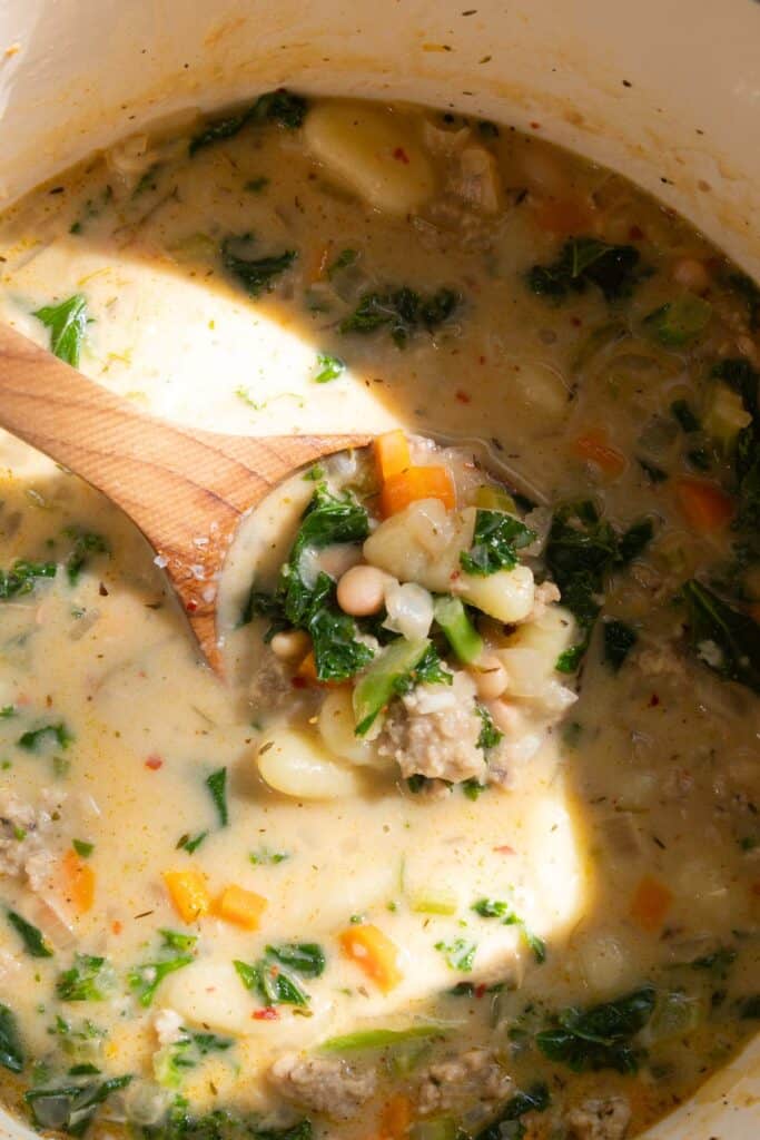 Brown ladle lifting a serving out of a pot of gnocchi soup.