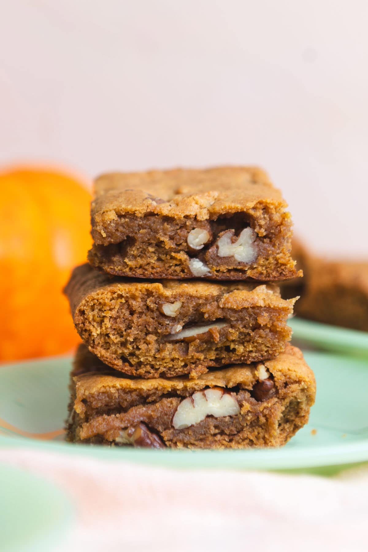 Three pumpkin pecan cookie bars stacked on top of each other on a jade green plate.