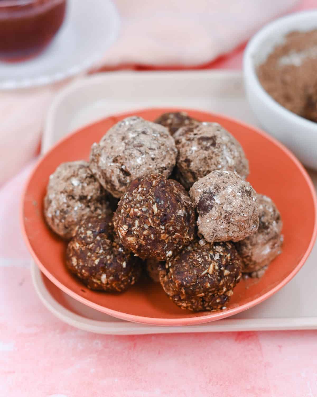 Energy balls in a pink bowl on a pink background.